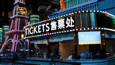 Illuminated ticket booth with vibrant neon lights at night, featuring colorful signage.