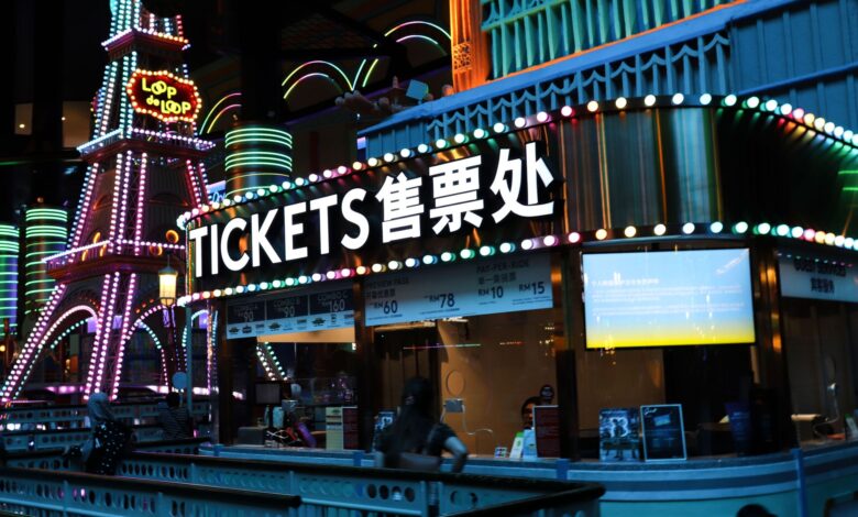 Illuminated ticket booth with vibrant neon lights at night, featuring colorful signage.