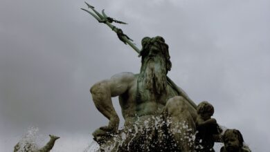 Low-angle shot capturing a dramatic statue of Poseidon with dynamic water splashes.