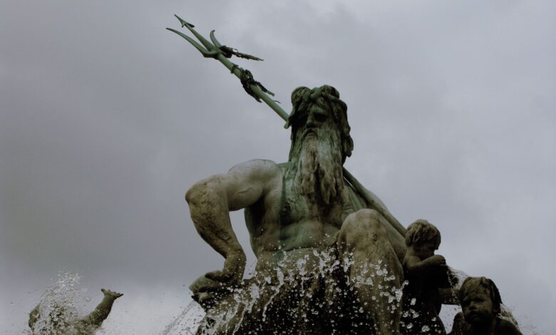 Low-angle shot capturing a dramatic statue of Poseidon with dynamic water splashes.