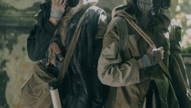 Two individuals in survival gear navigate a gritty urban post-apocalyptic setting.
