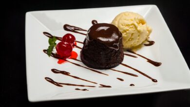 Delicious chocolate lava cake served with vanilla ice cream and cherries on a white plate.
