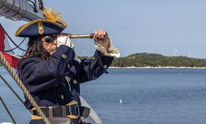 Pirate in blue outfit looking through spyglass on ship by the sea.