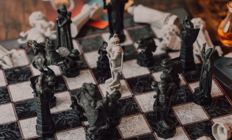 Close-up of intricately designed chess pieces on a marble-patterned board.