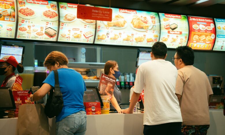 Customers ordering food at a fast food restaurant counter. Busy atmosphere.