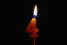 A lit number 4 candle against a black background, perfect for birthday celebrations and anniversaries.