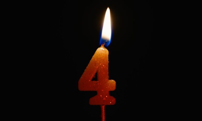A lit number 4 candle against a black background, perfect for birthday celebrations and anniversaries.