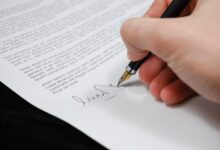 Close-up of a hand signing a legal document with a fountain pen, symbolizing signature and agreement.