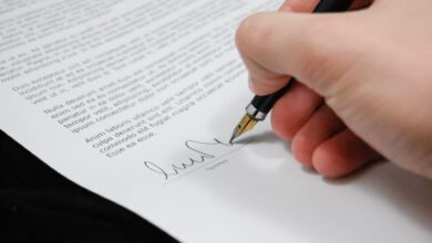 Close-up of a hand signing a legal document with a fountain pen, symbolizing signature and agreement.