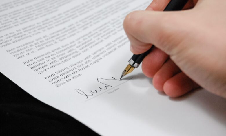 Close-up of a hand signing a legal document with a fountain pen, symbolizing signature and agreement.