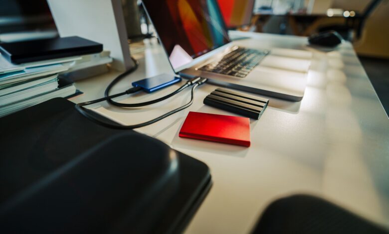 A neatly organized office desk featuring a laptop and several external hard drives, perfect for a digital workspace.