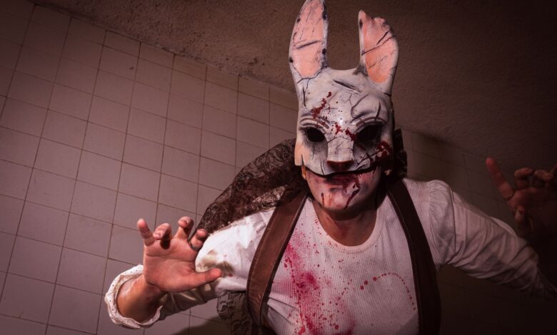 Close-up of a person in a bloody rabbit mask with ominous lighting.