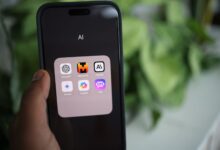 Close-up of a hand holding a smartphone with AI applications on screen.