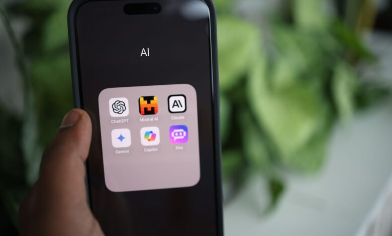 Close-up of a hand holding a smartphone with AI applications on screen.