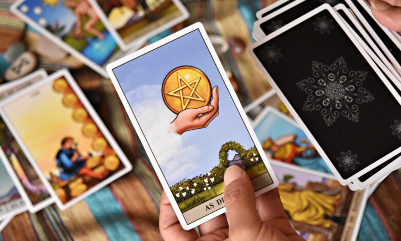 A person holds tarot cards in a colorful setting, showcasing divination tools and symbols.