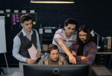 Group of professionals discussing a project at a computer in a modern office environment.