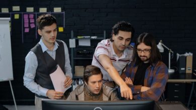 Group of professionals discussing a project at a computer in a modern office environment.