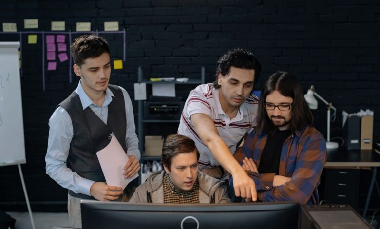Group of professionals discussing a project at a computer in a modern office environment.