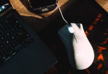 Stylish workspace setup featuring a gaming mouse and laptop with dramatic lighting.