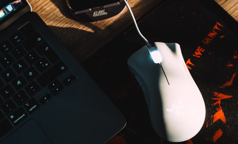Stylish workspace setup featuring a gaming mouse and laptop with dramatic lighting.