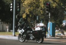 A police motorcycle stopped at a city intersection with traffic lights.