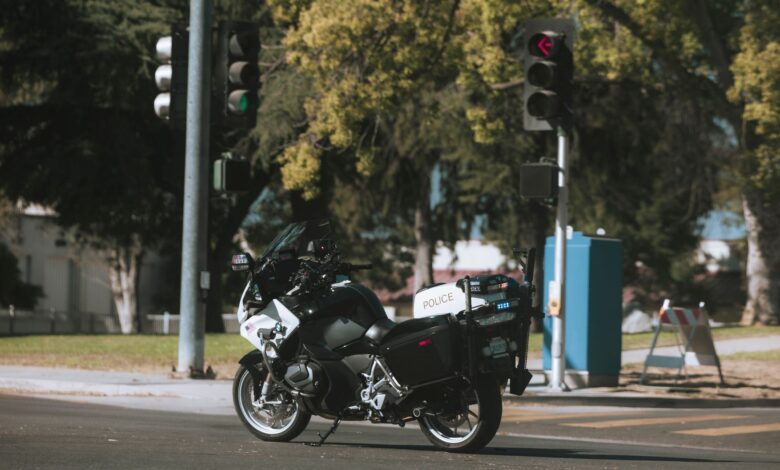 A police motorcycle stopped at a city intersection with traffic lights.