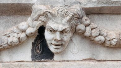 Detailed view of a classic Medusa face carving on ancient stone architecture.