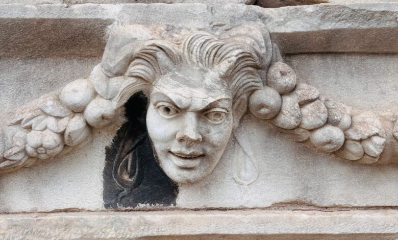 Detailed view of a classic Medusa face carving on ancient stone architecture.