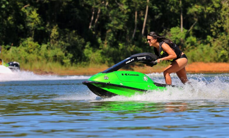A woman rides a green jet ski at high speed on a sunny day, showcasing excitement and fun.