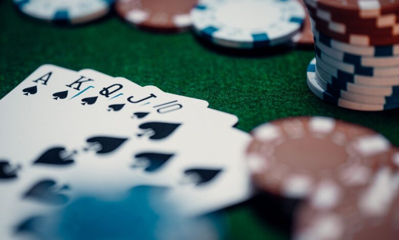 Close-up of a royal flush poker hand surrounded by colorful chips on a green table.