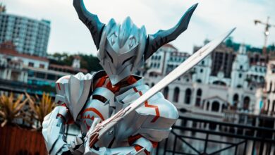 A person in futuristic armor with a sword posing outdoors, showcasing cosplay artistry.