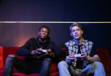 Two young men enjoying video games together on a couch, capturing leisure and friendship.