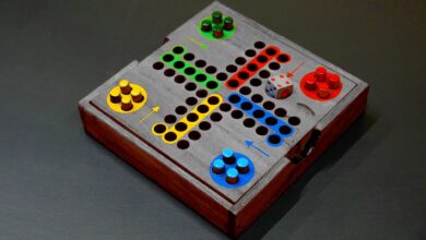 A vibrant wooden board game with colorful pieces and a die on a dark surface.