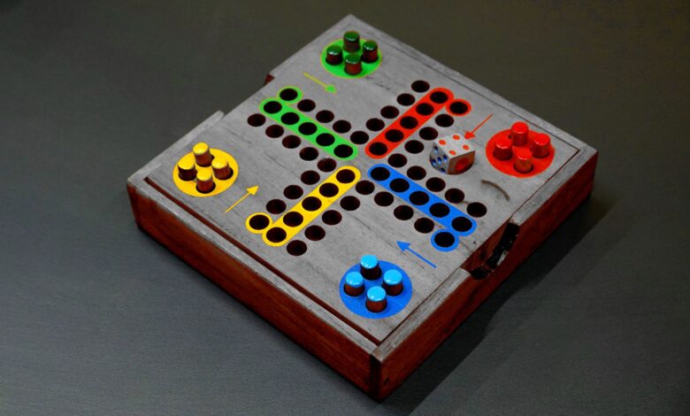 A vibrant wooden board game with colorful pieces and a die on a dark surface.