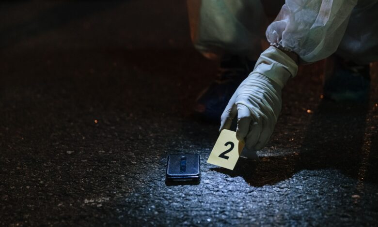 Forensic investigator examining evidence in a city street at night.