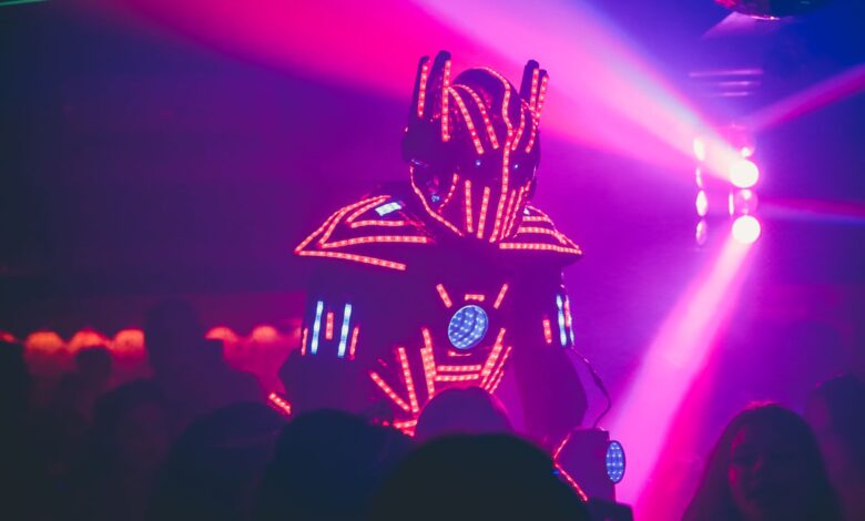 Anonymous person in illuminated futuristic costume of robot performing show on stage of modern nightclub with neon illumination