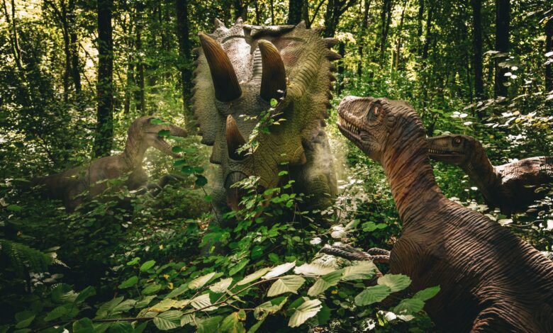 Realistic dinosaur models in a lush forest create an educational prehistoric scene.