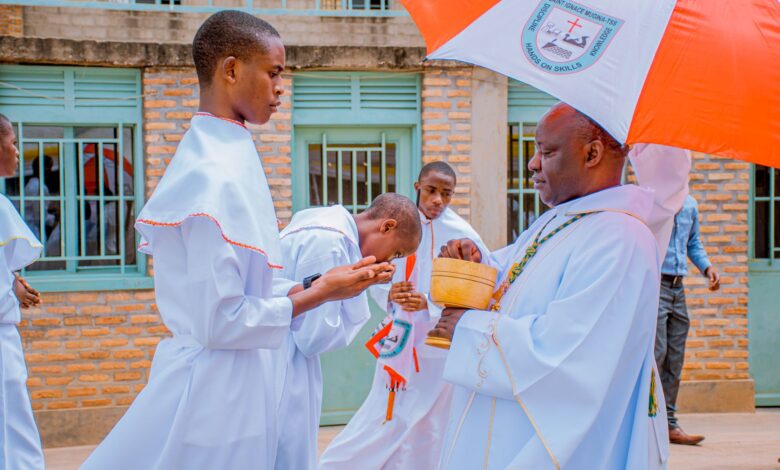 A priest providing communion to altar boys during an outdoor religious ceremony.