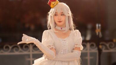 Cosplayer dressed as an elegant princess with white hair and gown, wearing a red crown.