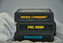 Close-up of vintage Atari game cartridges for Missile Command, Pac-Man, and Defender.