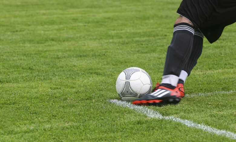 Dynamic shot of a soccer player kicking the ball on a grassy field, showcasing fast-paced sports action.