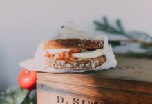 Close-up of a bacon and egg sandwich on sourdough, styled on a wooden box.