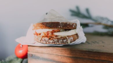 Close-up of a bacon and egg sandwich on sourdough, styled on a wooden box.