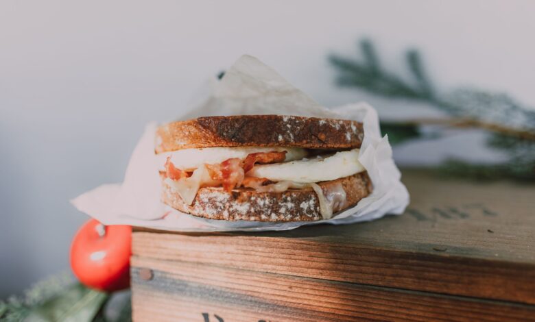 Close-up of a bacon and egg sandwich on sourdough, styled on a wooden box.