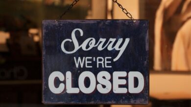 A 'Sorry We're Closed' sign hangs in a shop window, indicating closure.