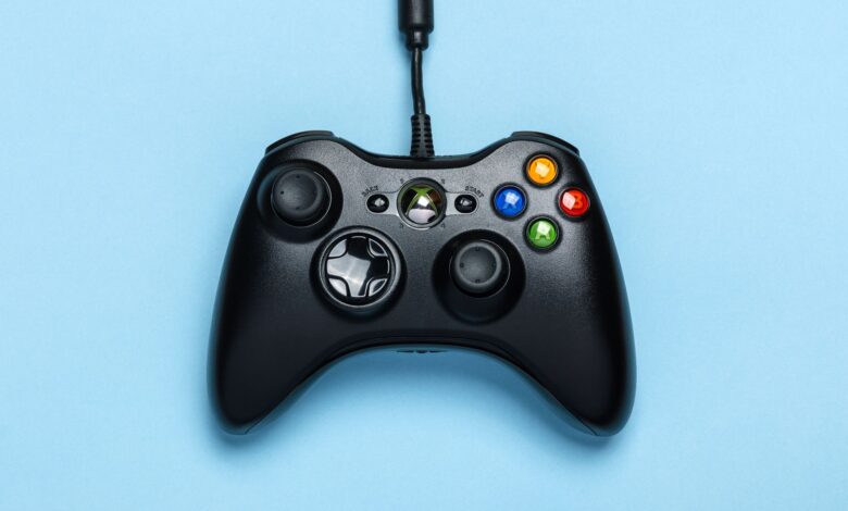 Black video game controller isolated on a blue background for gaming enthusiasts.