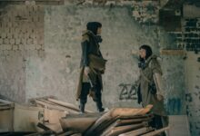 Two people in urban survival gear explore a dystopian, abandoned building setting.