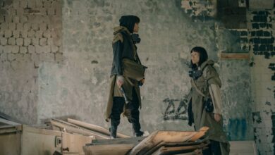 Two people in urban survival gear explore a dystopian, abandoned building setting.