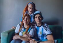 Group of fans in Argentina soccer jerseys expressing excitement indoors.