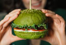 A delectable green veggie burger held in hands, perfect for healthy eating enthusiasts.
